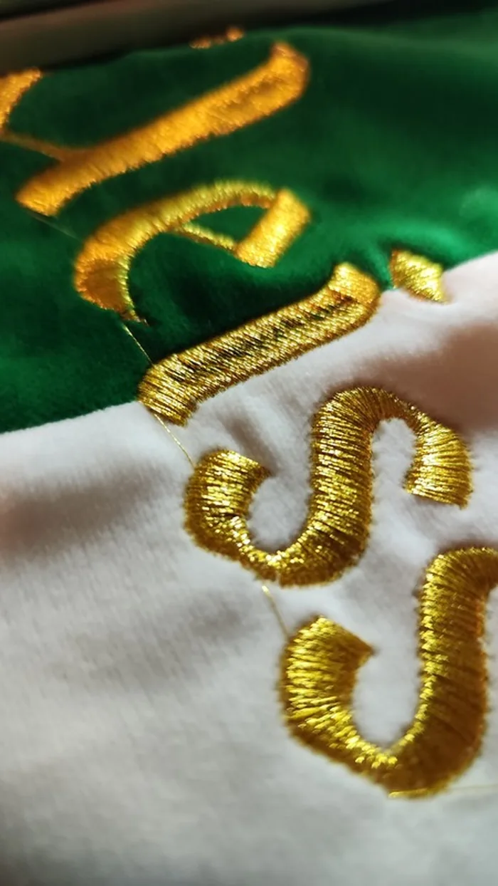 Goldene Stickerei-Buchstaben im Nahaufnahme-Detail