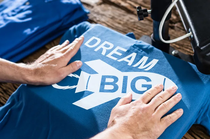 Aufbringen eines Dream-Big-Transferdrucks auf ein blaues T-Shirt